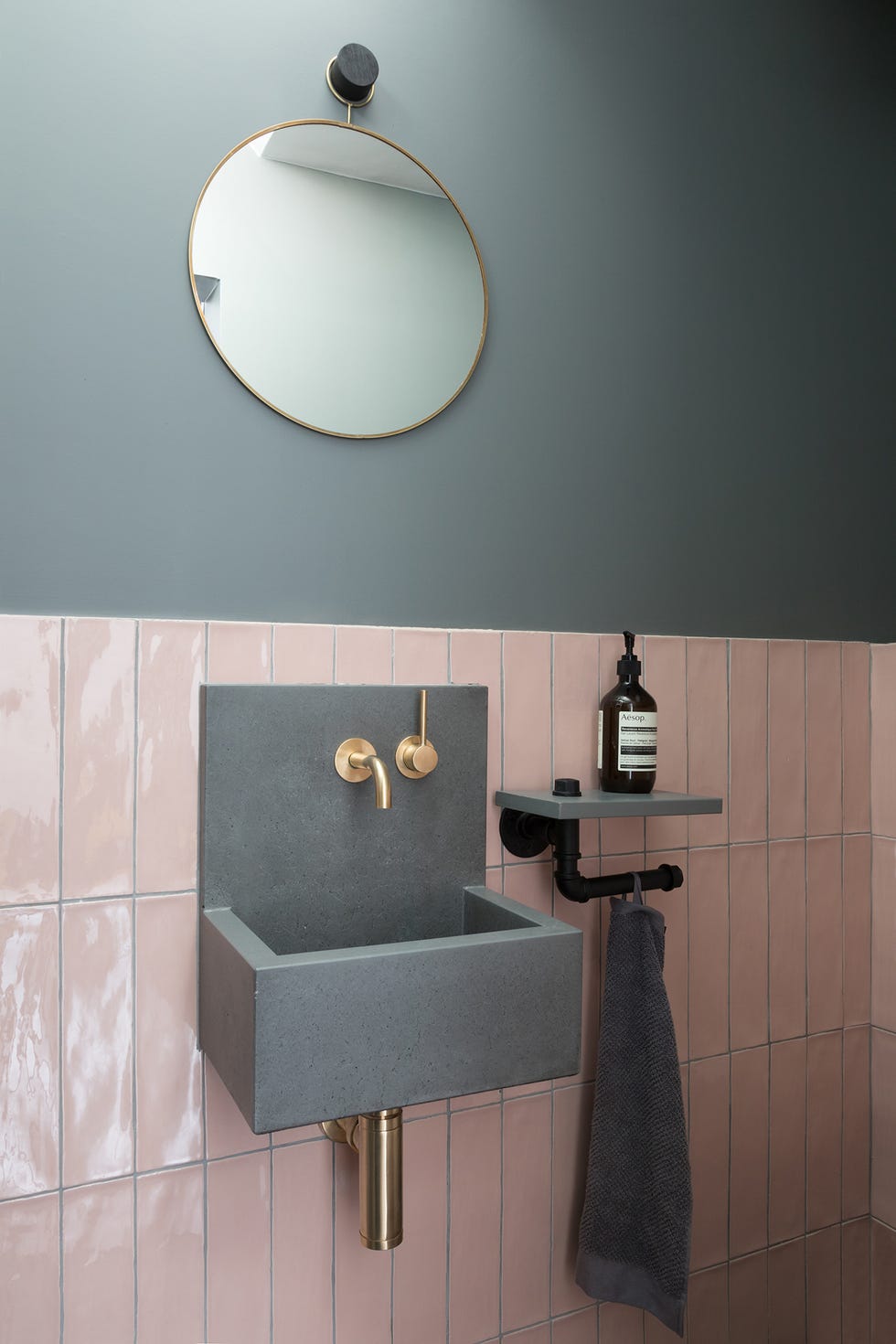 aseo de estilo industrial con pared a dos colores, azulejos en rosa empolvado, lavamanos flotante gris y grifería dorada