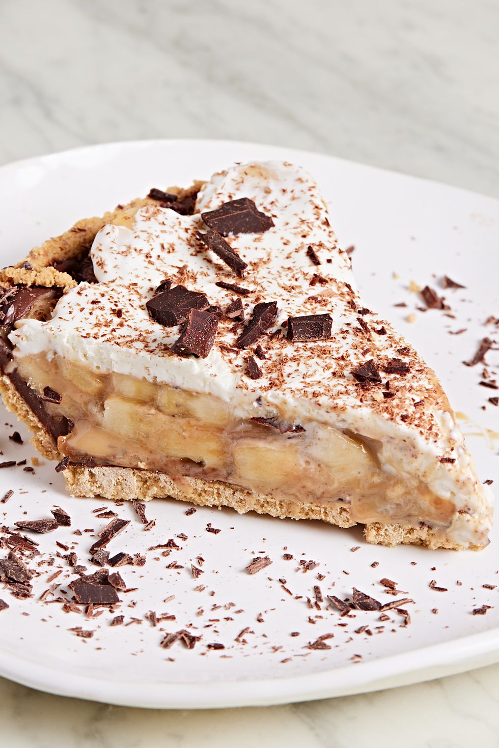 slice of banoffee pie topped with whipped cream and chocolate shavings on a white plate