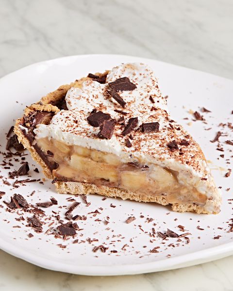 slice of banoffee pie topped with whipped cream and chocolate shavings on a white plate