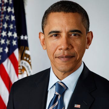 barack obama in suit and tie, posing in front of us flag