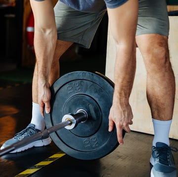 man putting weight on barbell bar