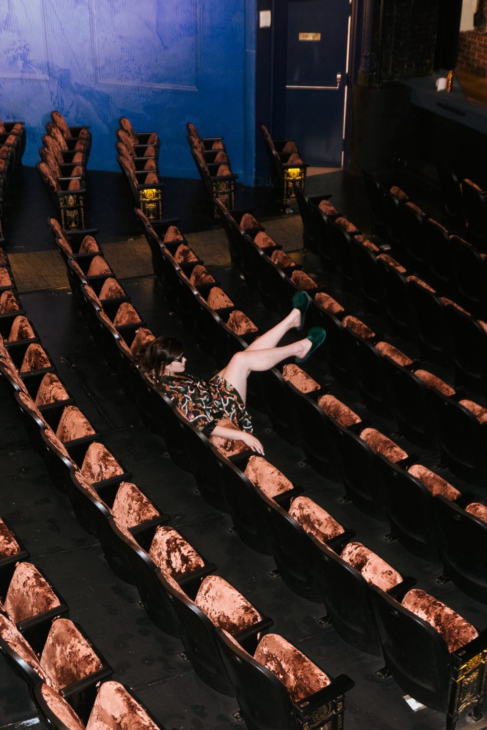 a person reclined in a theater seat surrounded by empty seats