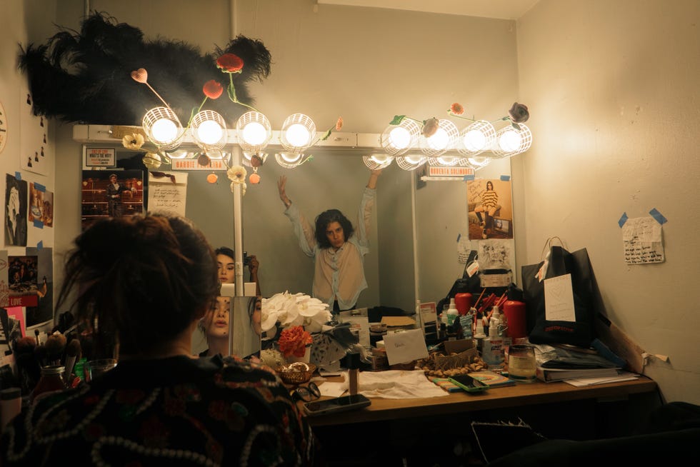 vanity area with multiple light bulbs and a person posing in front of a mirror