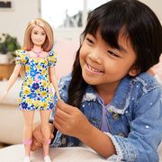 young girl playing with barbie in floral dress