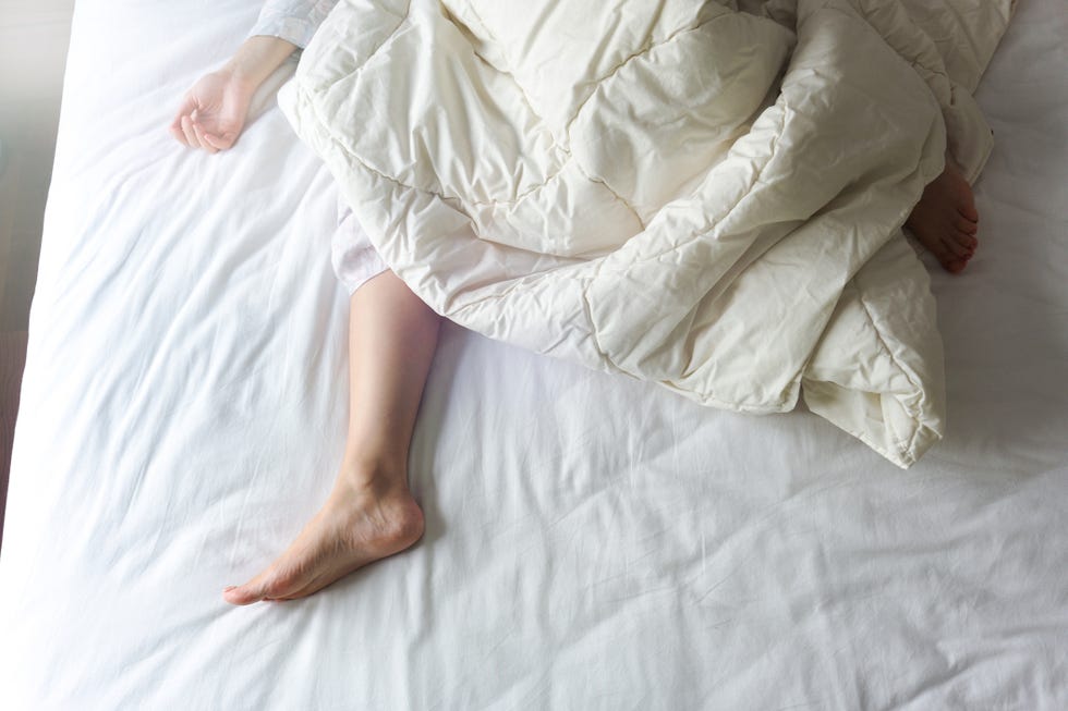 bare feet of a young woman on white bed