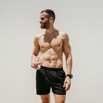 barechested male athlete holding a bottle of water