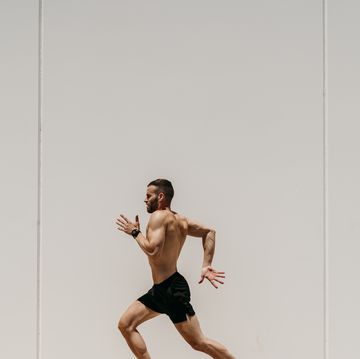 barechested male athlete running along a wall