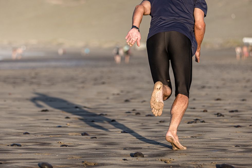 barefoot athlete running on the beach