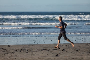 barefoot man in sports clothes running on the beach