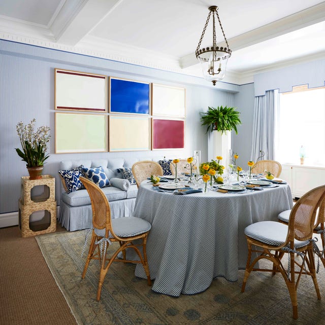 a blue and white dining room with a grid of modern art of the wall