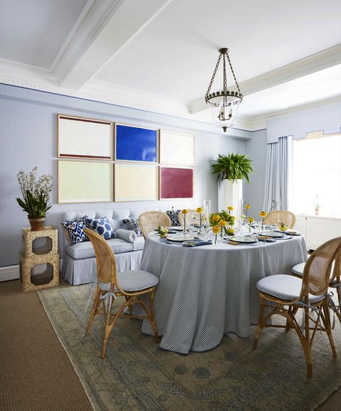 a blue and white dining room with a grid of modern art of the wall