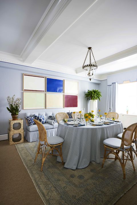 a blue and white dining room with a grid of modern art of the wall
