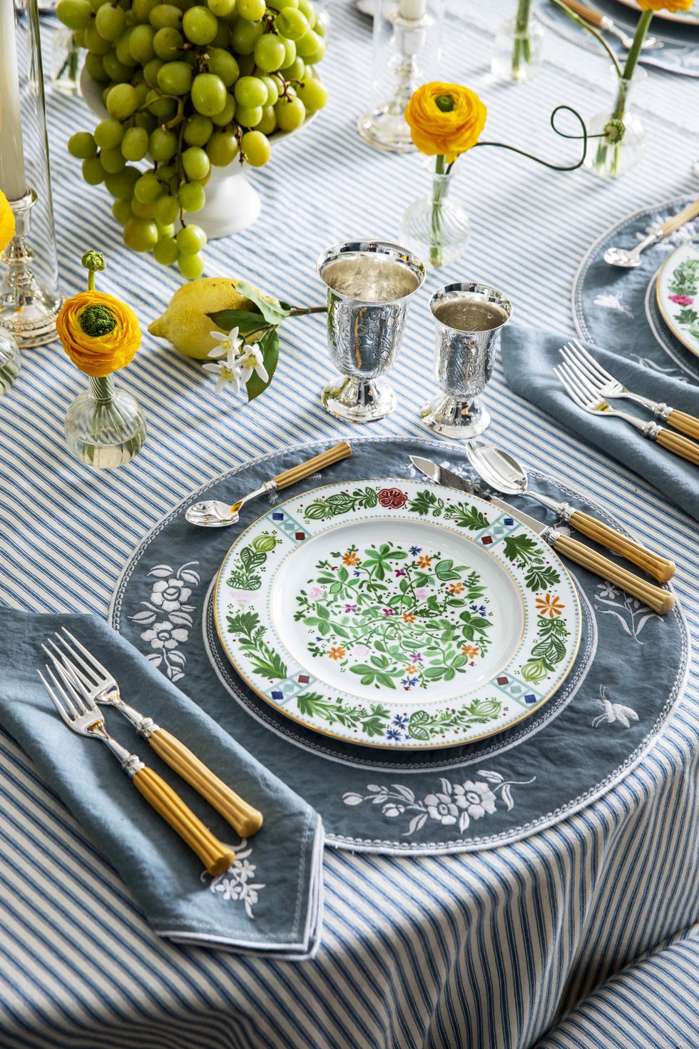a table setting with blue and white tablecloth and green and white floral plates