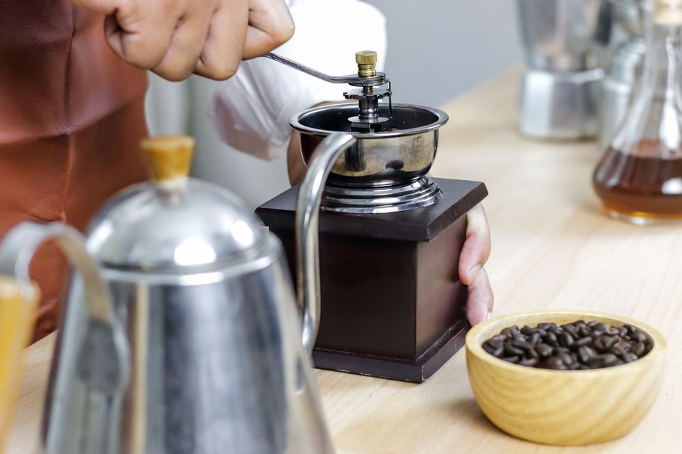 barista preparing coffee with grinders, coffee bean and hot pot