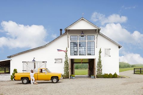 white converted barn home with yellow pickup truck out front