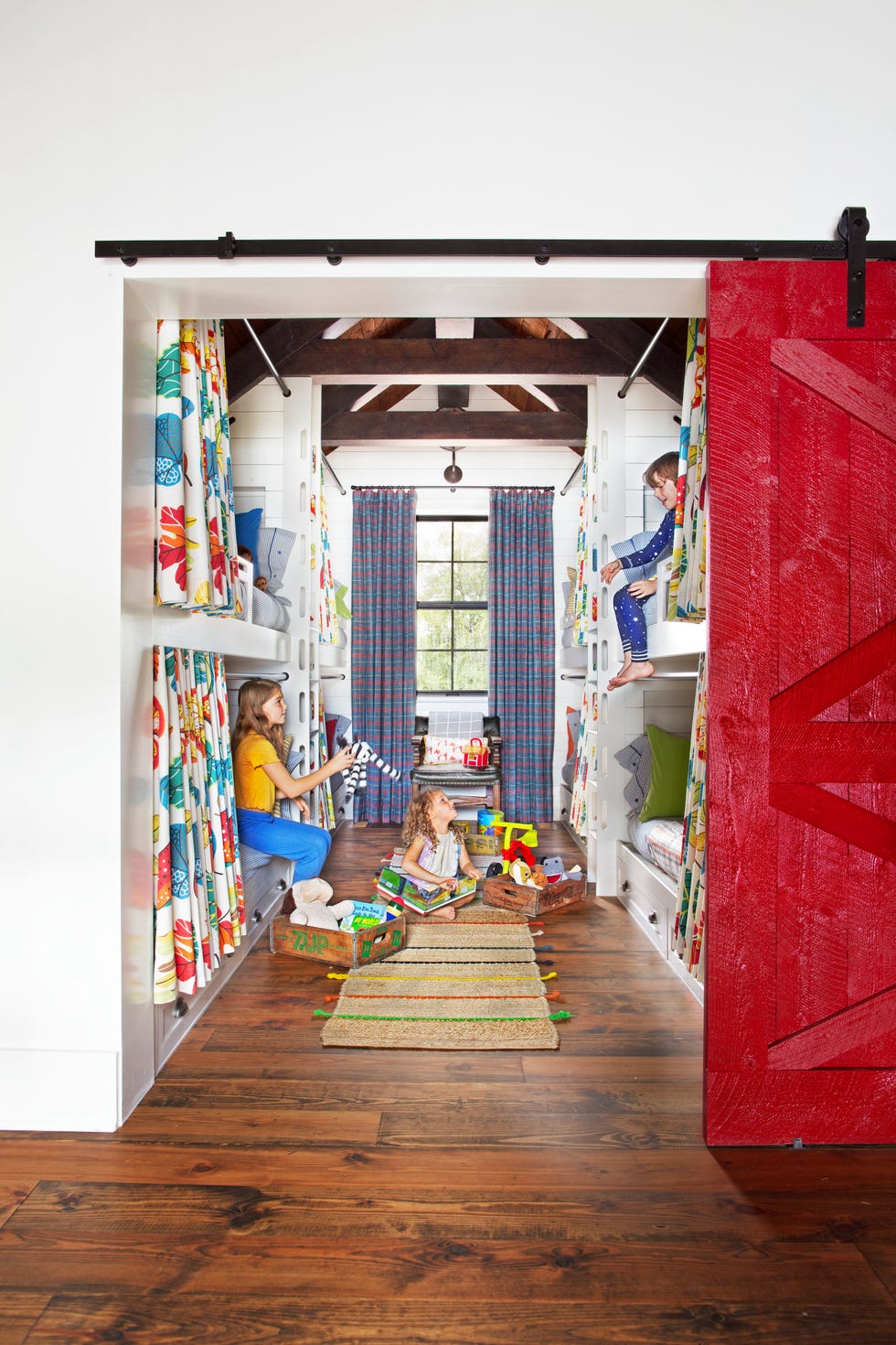 colorful bunk room with red barn door and plaid curtains