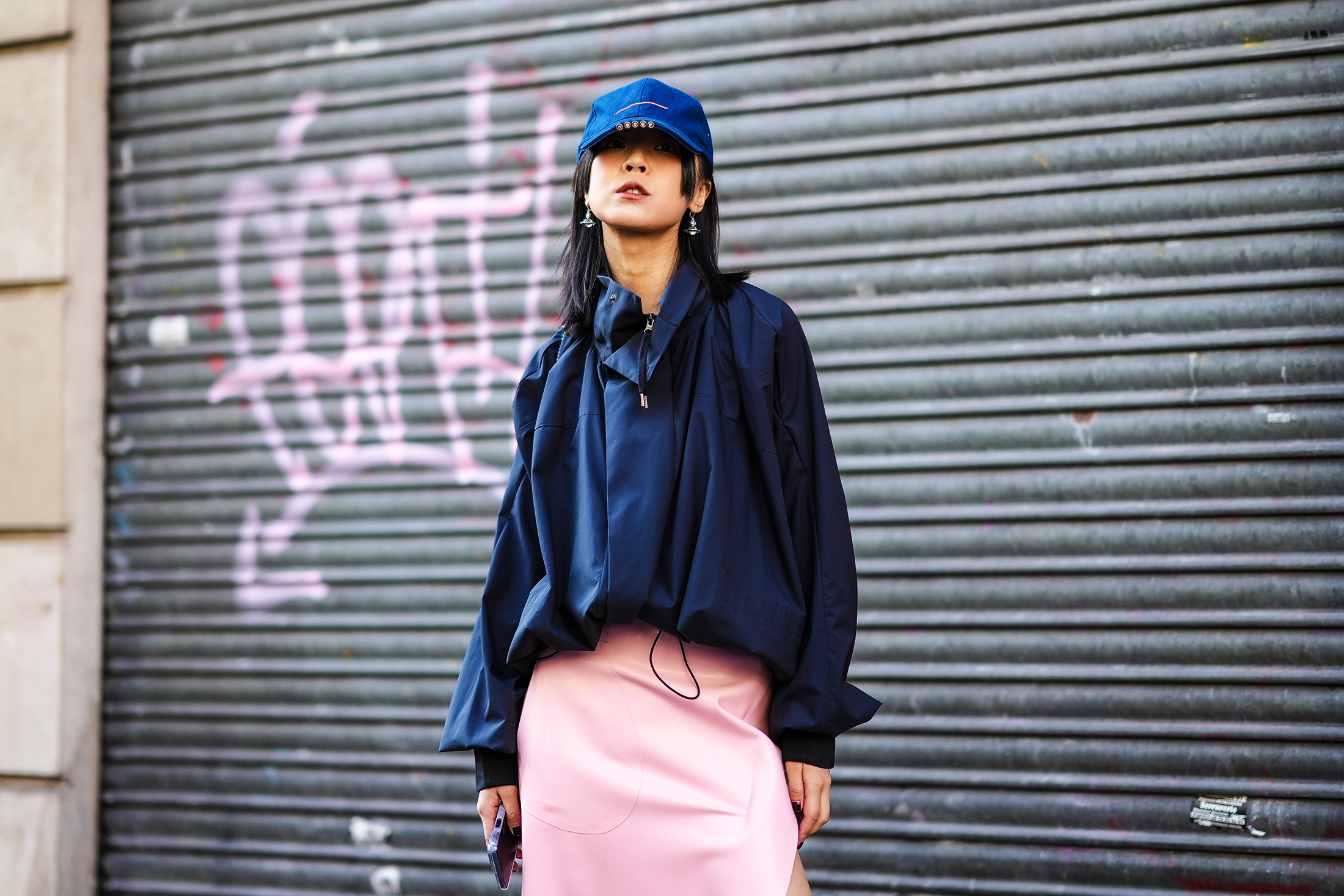 American stylish young woman in a trendy black baseball cap in a leather  white jacket in