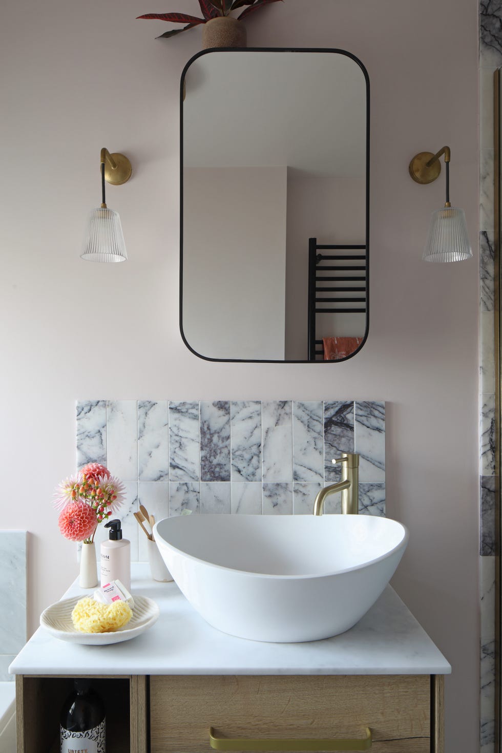 a basin area in a family bathroom with modern curved basin and statement marble tiles