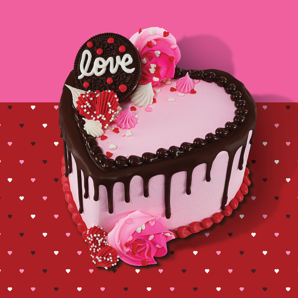 heartshaped cake decorated with pink frosting chocolate drip and various toppings