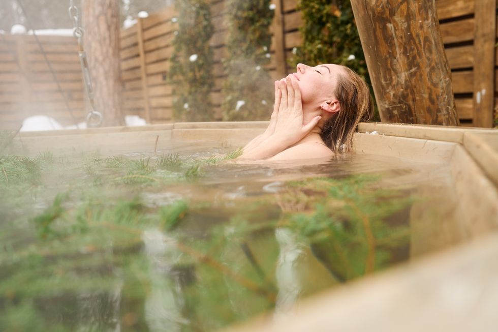 woman enjoying a peaceful moment in a steamy hot tub on a snowy day