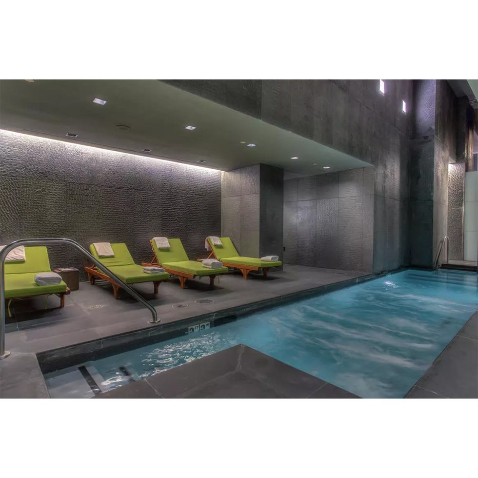 indoor spa area with lounge chairs and a pool