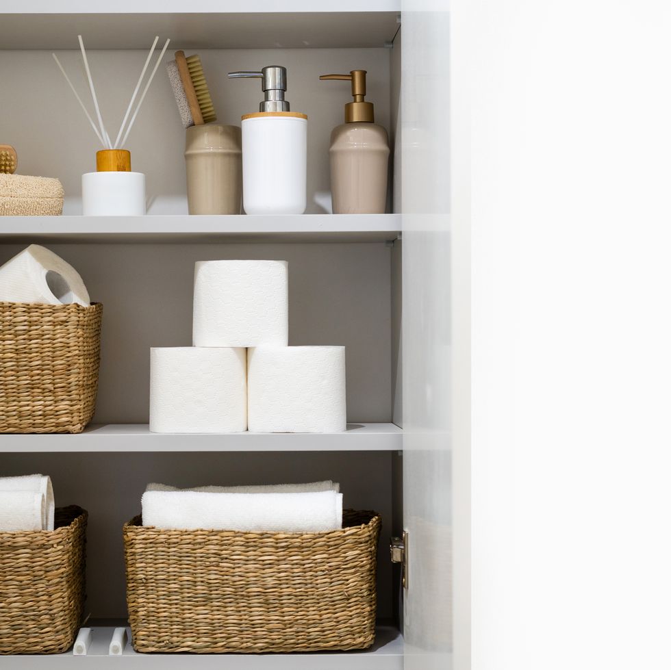 bathroom cabinet with organized supplies, fresh towels, toilet paper and dispenser bottles with soap