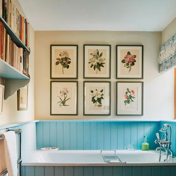 soaking tub with wood panel surround painted turquoise, gallery wall of framed botanicals on cream wall above