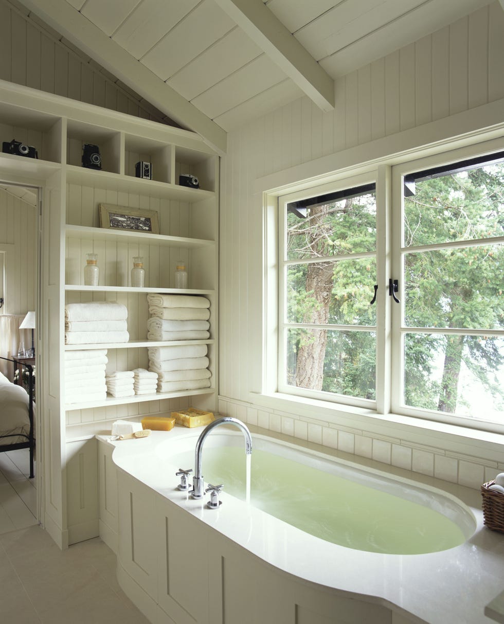 Bathroom interior bathroom interior with a large white tub, built in shelves, and a view towards some trees