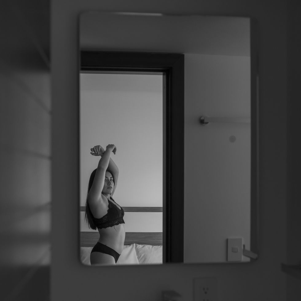 bathroom mirror with the reflection of a young woman in lingerie, who is in the room