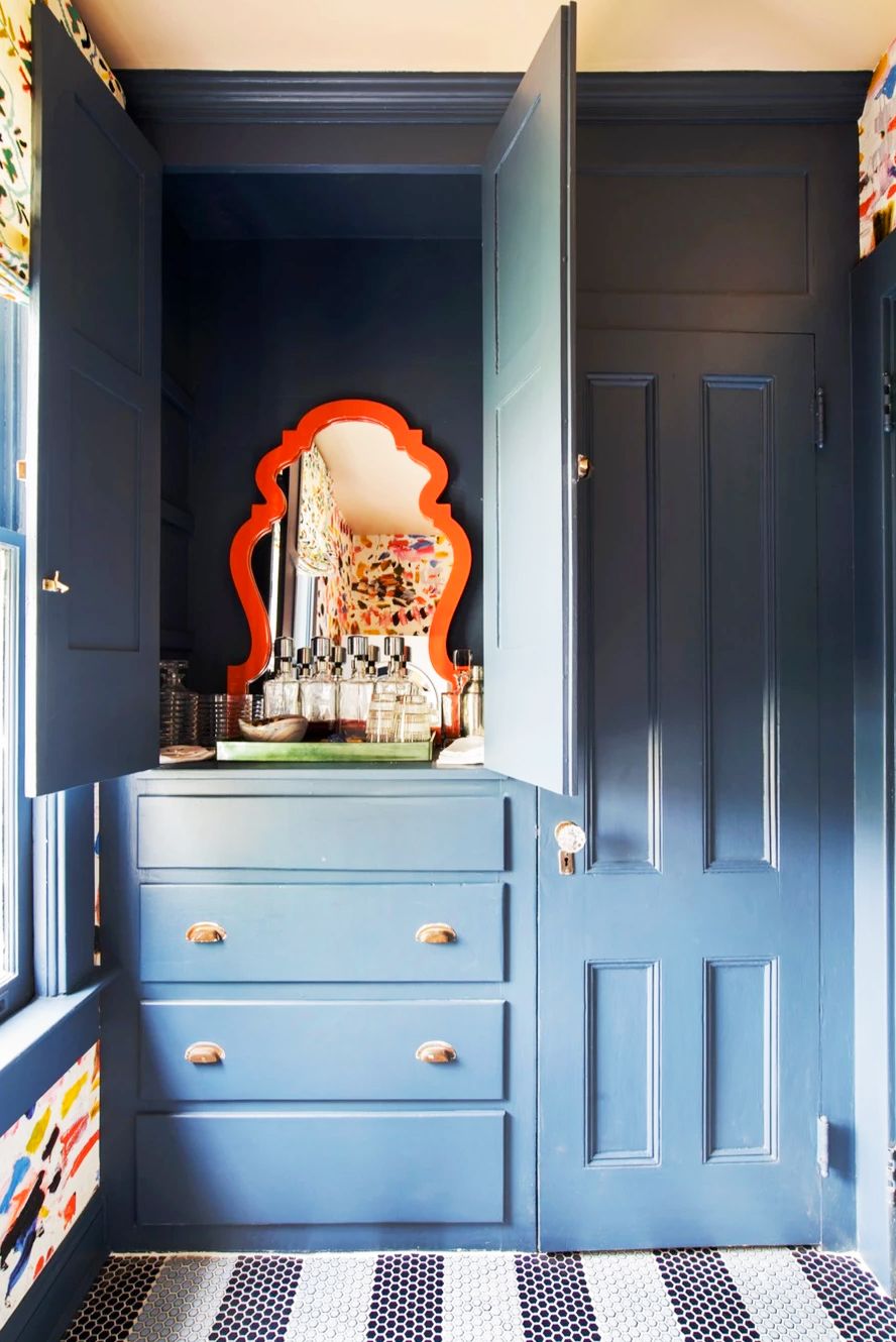 blue bathroom cabinet with hidden vanity and orange mirror