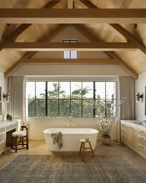 with a waterworks tub under a wall of windows and wooden beams, this airy bath by amber interiors design studio feels like a spa