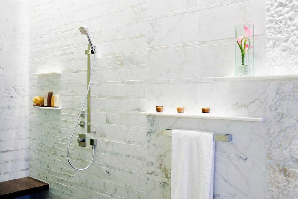 bathroom wall with two streamlined and low profile shelves that hold candles and a flower