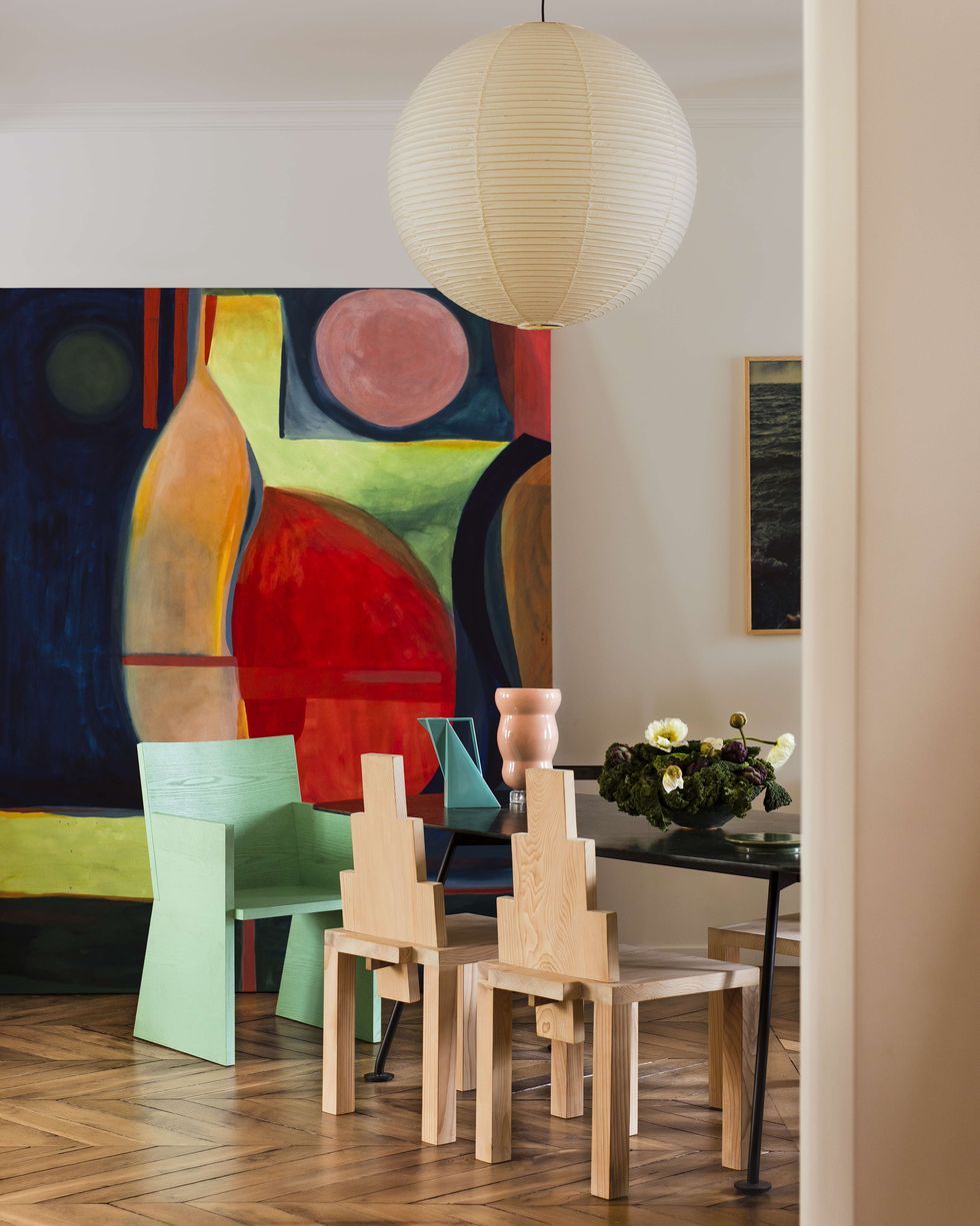 a room with a table chairs and a painting on the wall