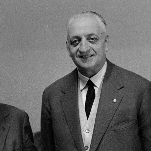 enzo ferrari smiles at the camera, he wears a three piece suit and tie