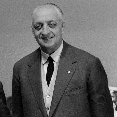enzo ferrari smiles at the camera, he wears a three piece suit and tie