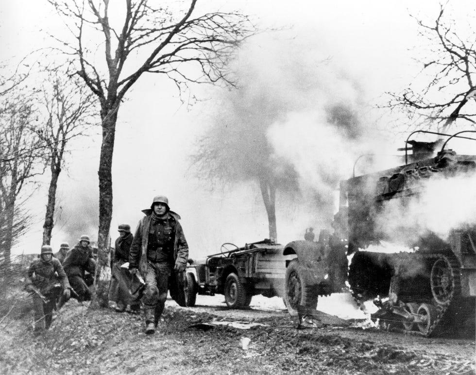 Tijdens de Slag om de Ardennen lopen Duitse infanteristen langs brandende Amerikaanse voertuigen Konvooien van de Derde Rijk werden vaak aangevoerd door buitgemaakte tanks om de Geallieerde troepen te verwarren