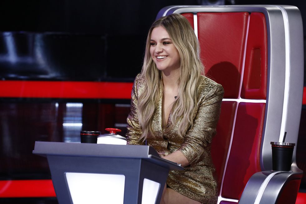 kelsea ballerini sitting in a large red and silver chair and smiling