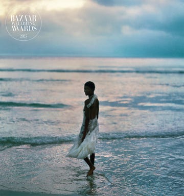 person in a white dress walking on the beach at sunset
