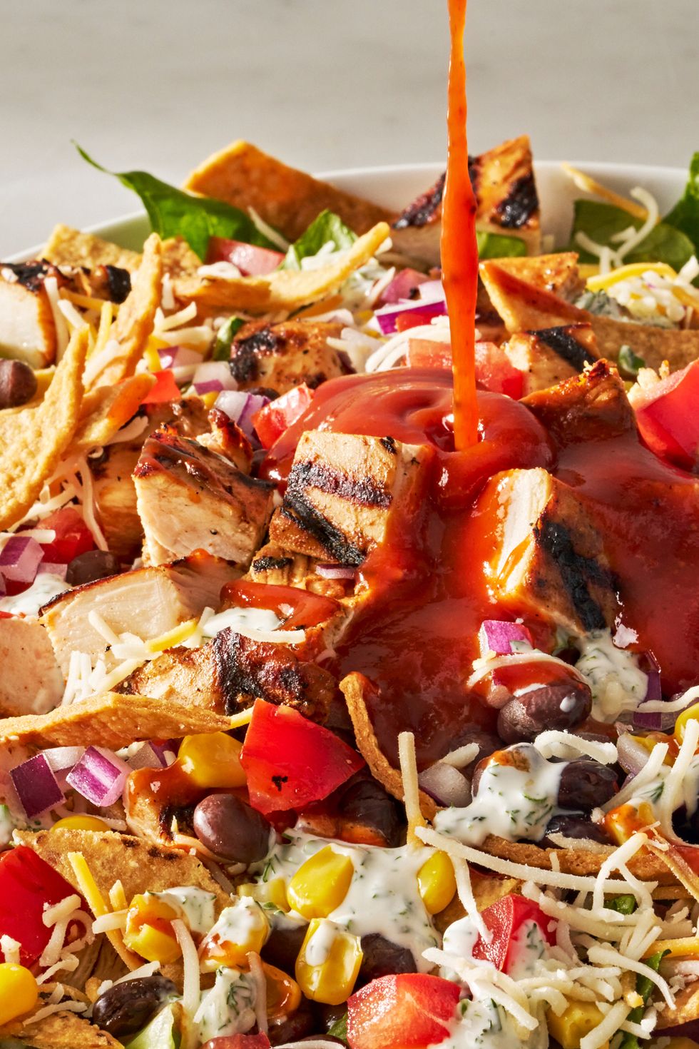 bbq chicken salad with barbecue sauce, chicken, toppings, and a creamy dressing