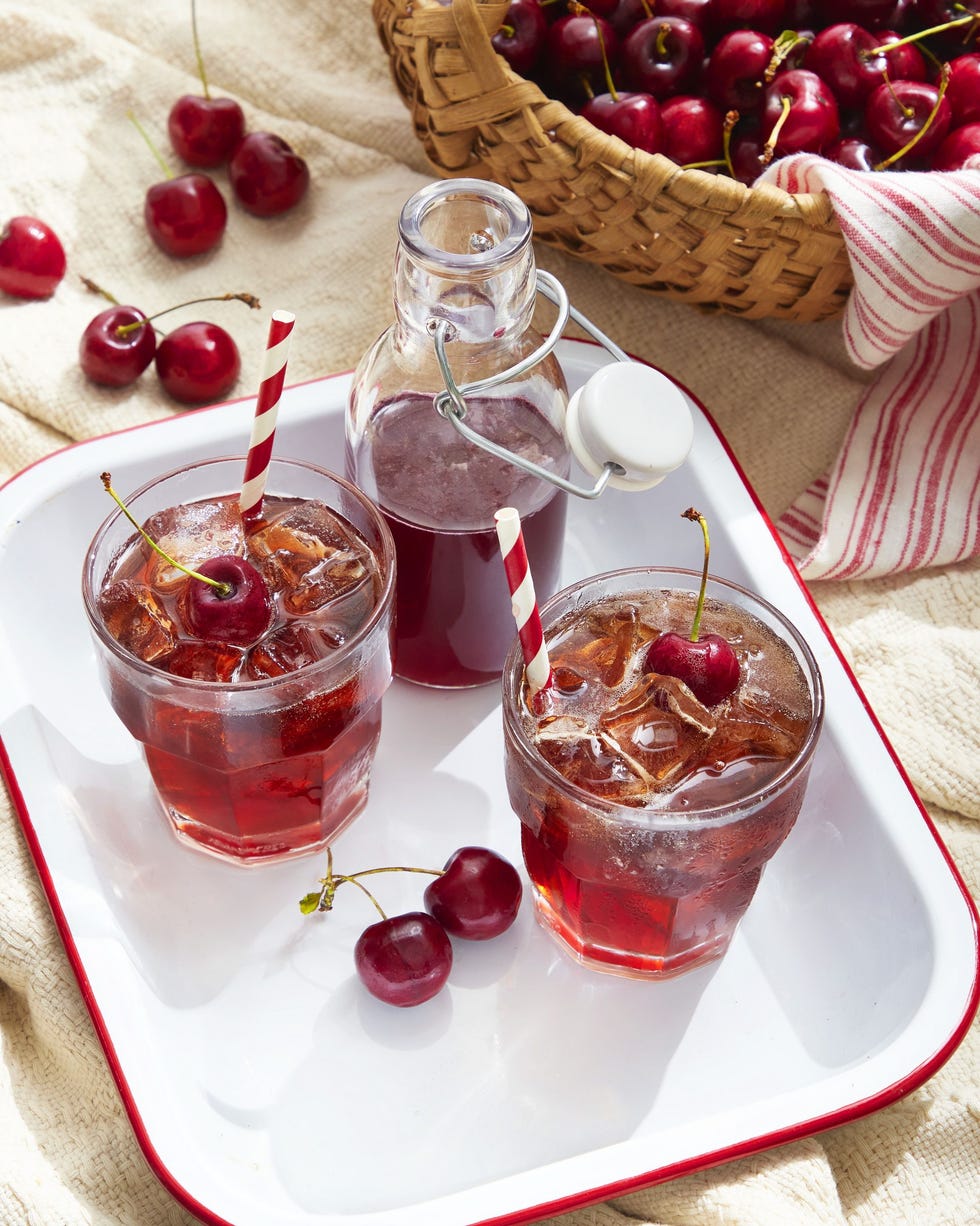 cherry syrup and rum soda in glasses with ice and fresh cherries for garnish