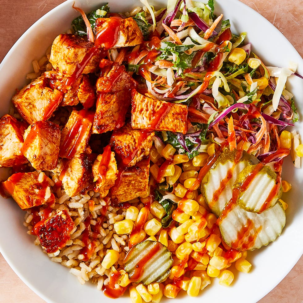 bbq chicken in a grain bowl with corn, pickles, and slaw