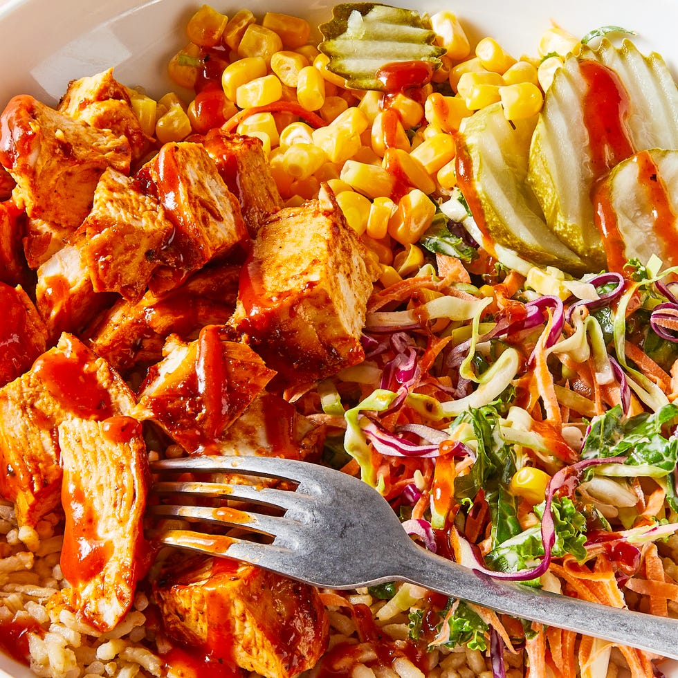 bbq chicken in a grain bowl with corn, pickles, and slaw