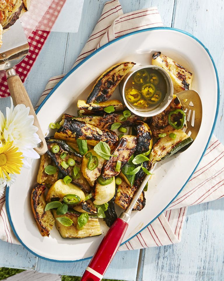 grilled summer squash with lemon scallion dressing on a platter with a spatula for serving