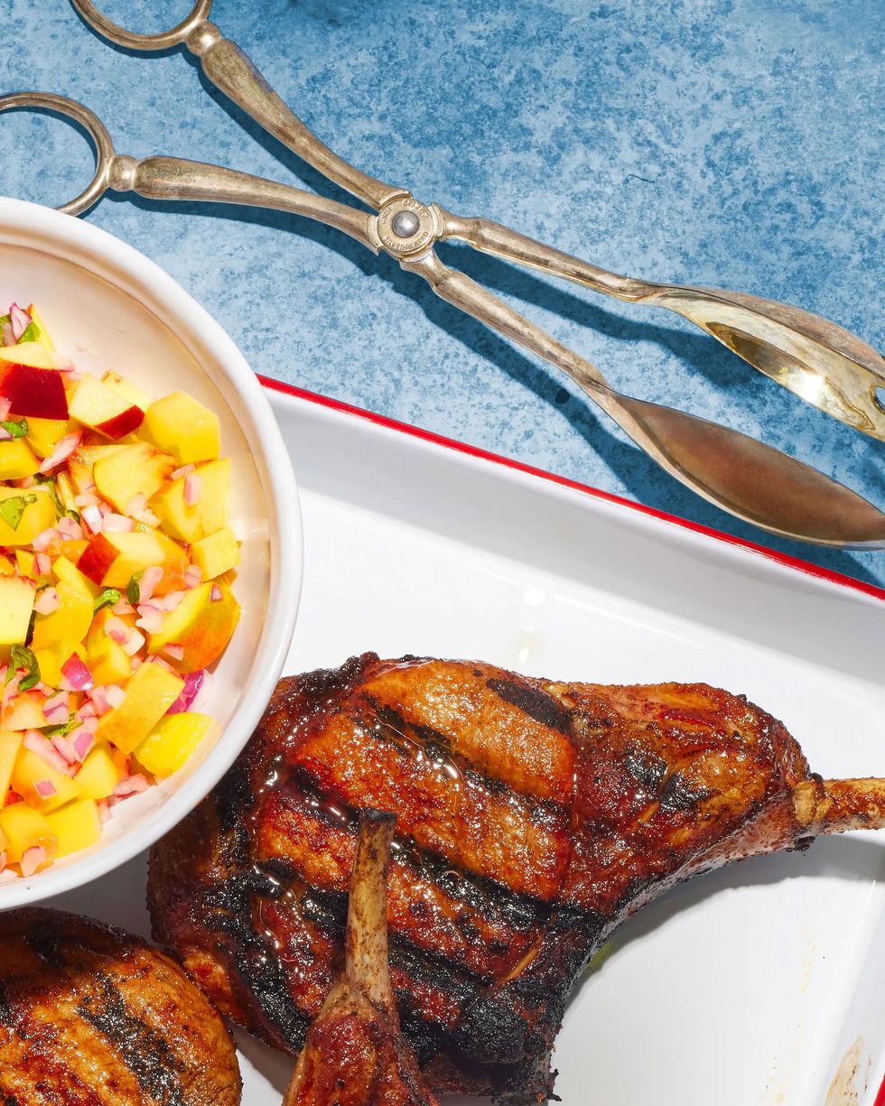 fresh summer peach relish in a bowl with a spoon on a tray of grilled pork chops