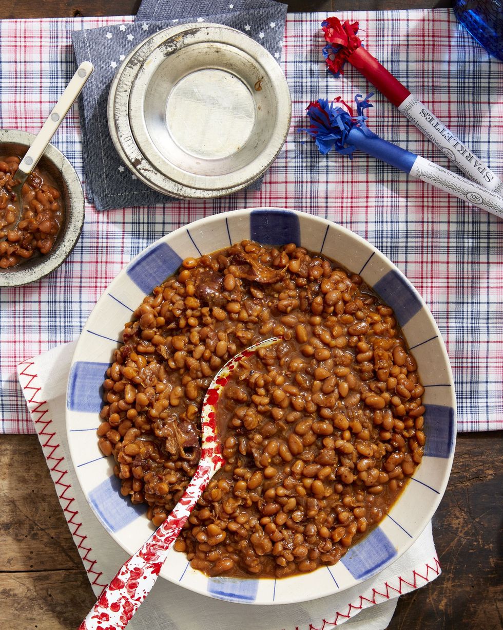 root beer baked beans in a blue and white striped bowl with a red and white speckled spoon