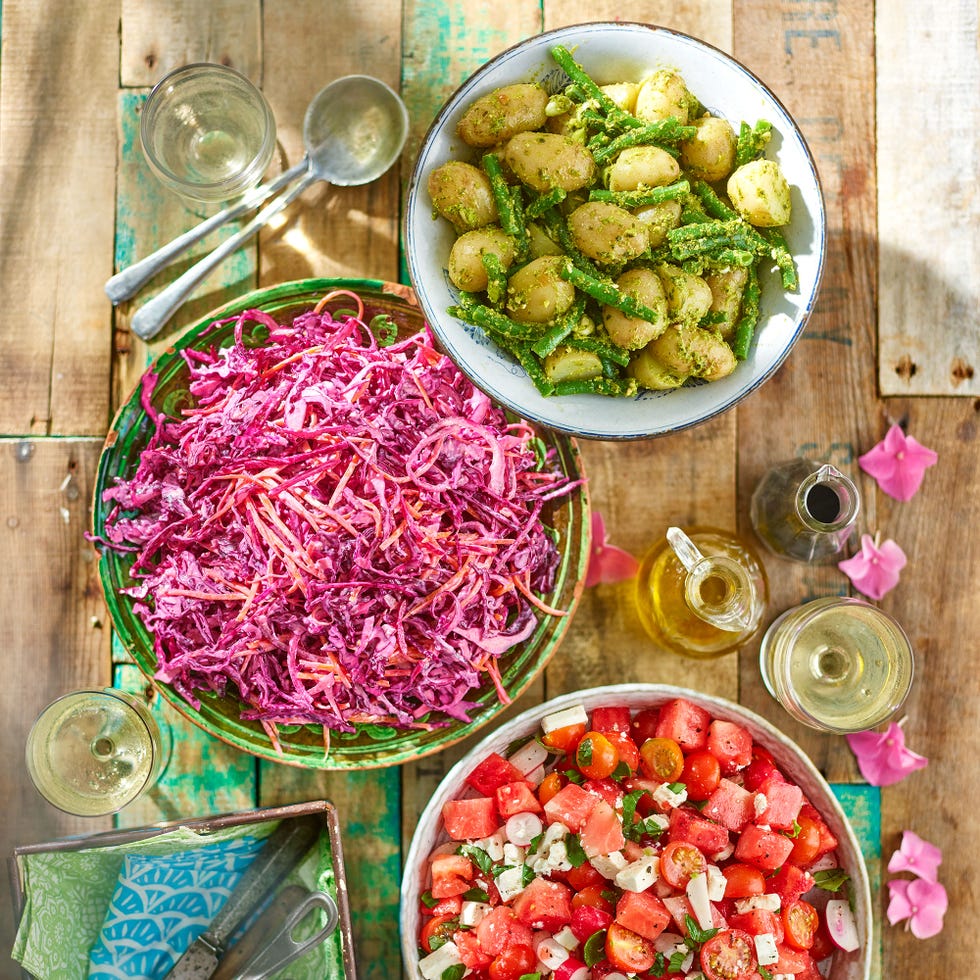 a collection of vibrant salads served in bowls on a wooden table