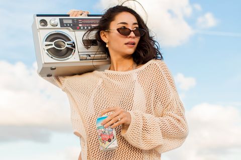 woman carrying stereo and beach juice canned rose