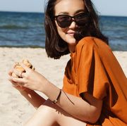 woman in sunglasses eating a burger on the beach