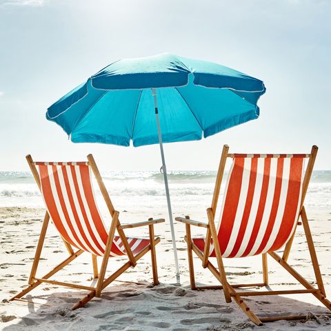 still life shot of two deck chairs under an umbrella on the beach