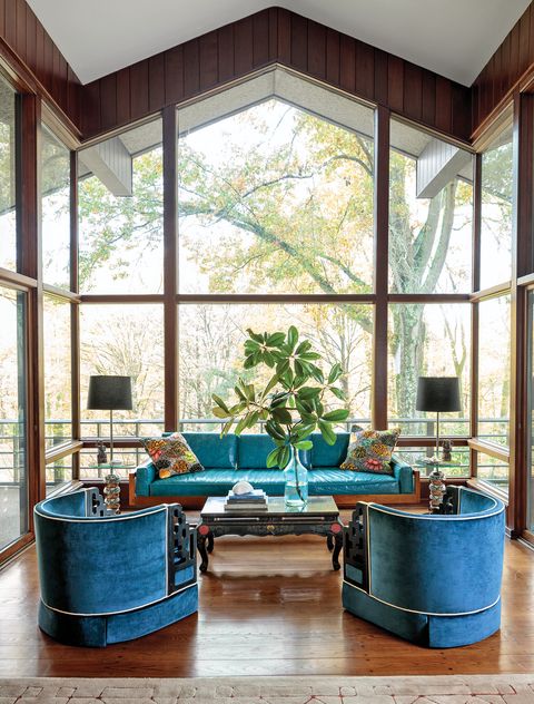 Glass-enclosed living room with high ceilings and blue furniture
